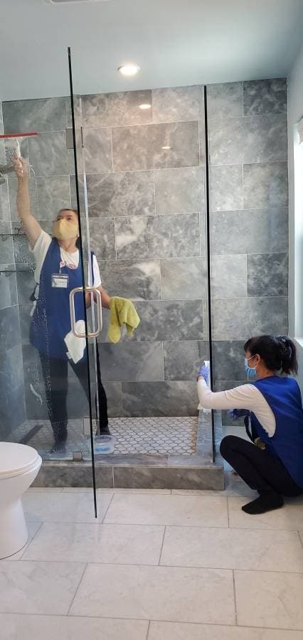 Professional cleaner scrubbing shower tiles during deep bathroom cleaning